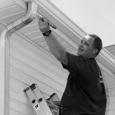 a painting contractor brushing paint on an aluminum leader